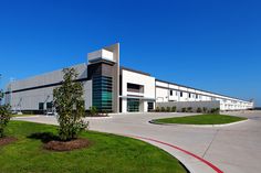 an industrial building with lots of windows and grass in the front yard, on a sunny day