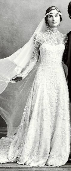 a man and woman standing next to each other in wedding dresses with veils over their heads