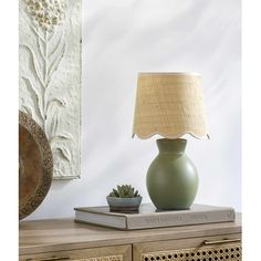 a green lamp sitting on top of a table next to a book and potted plant