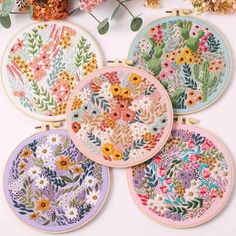 four embroidery hoops with flowers on them and one has a flower arrangement in the middle