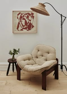 a chair and lamp in front of a painting on the wall