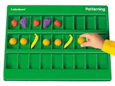 a child's hand playing with a matching fruit and veggie tray