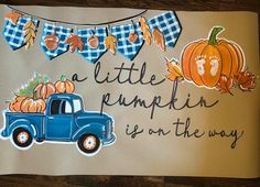 a blue truck with pumpkins and bunting on it's side sitting in front of a wooden table