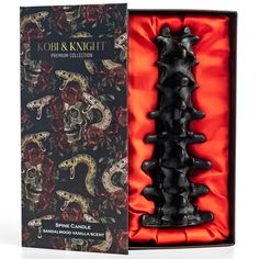 a black candle in a gift box with red roses and skulls on the packaging side