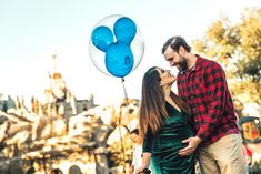 a man and woman standing next to each other in front of a mickey mouse balloon