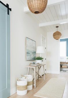 a room with white walls and wooden floors, two baskets on the floor next to a blue door