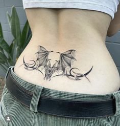 a woman's lower back tattoo with two bats on it