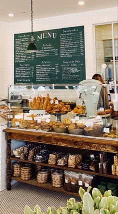 a display case in a bakery filled with lots of pastries and desserts next to a chalkboard menu