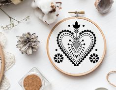 a cross stitch pattern in the shape of a heart on a white table next to cotton and other crafting supplies