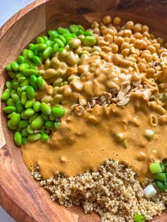 a wooden bowl filled with rice, peas and other food items on top of it