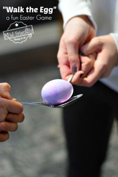 a person holding a spoon with an egg on it