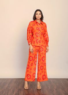 *This delightful ensemble is designed to captivate with its lively floral print and eye-catching orange hue, bringing a burst of freshness to your wardrobe.  *The set comprises a chic collared shirt and a pair of tailored pants, creating a harmonious fusion of style and comfort.  *The unique detail of a belt tie-up in the back adds a playful and flattering element, allowing you to cinch the waist for a customized fit and a graceful silhouette.  *The accompanying pants are designed for ultimate c Orange Floral Print Sets For Spring, Orange Floral Print Spring Sets, Spring Floral Print Orange Sets, Spring Orange Floral Print Sets, Summer Orange Floral Print Sets, Orange Printed Pants For Summer, Spring Long Sleeve Printed Pant Set, Orange Floral Print Pants For Spring, Orange Printed Cotton Set