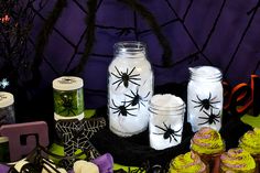 some jars with spider webs on them are sitting next to other halloween decorations and candles