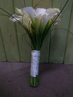 white flowers are in a vase on the floor