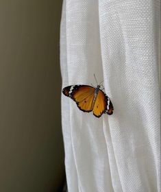 a yellow butterfly sitting on top of a white curtain