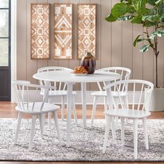 a white table with four chairs and a potted plant in the corner next to it