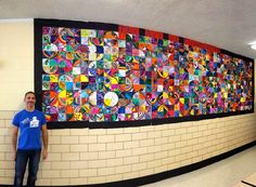 a man standing in front of a wall covered with colorful images and circles on it