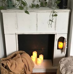 a fireplace with candles in front of it and a blanket on the floor next to it