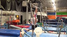 a woman is doing aerial acrobatics in an indoor gym with blue and green mats