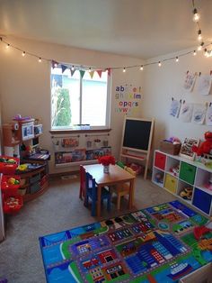 a child's playroom is shown with toys on the floor and lights strung from the ceiling