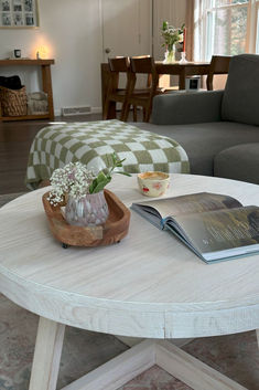 a coffee table with an open book on it and a flower vase sitting on top