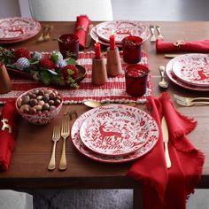 the table is set with red and white plates, napkins, silverware, and candy