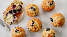 muffins with blueberries and cream cheese are on a marble surface next to a knife