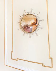 there is a mirror on the wall in the room that has been decorated with gold trim