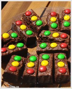 chocolate brownies with m & m candies on top are sitting on a glass plate