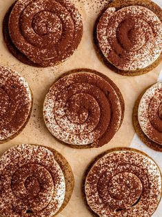 several cookies with chocolate frosting and sprinkles on a sheet of parchment paper