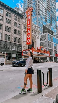 a woman standing on the side of a street next to a sign that says chicago