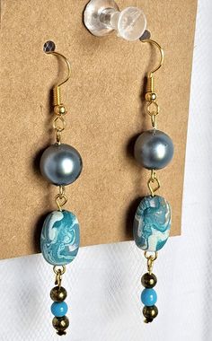 Add a touch of bohemian style to your outfit with these beautiful turquoise, white and gold tone clay/plastic/brass bead dangle earrings. The earrings feature a 2" length with gold tone hypoallergenic hooks, plastic turquoise color and brass round beads.   These earrings are perfect for those who love unique and handmade jewelry. They are suitable for any occasion and will complement any outfit. These earrings are not only stylish but also hypoallergenic, making them suitable for those with sensitive skin. Get these stylish dangle earrings today and add a touch of bohemian chic to your wardrobe. **FREE SHIPPING!! *Item has been stored in a smoke and cat free environment.  *Item will be shipped USPS Ground Advantage unless otherwise requested. Blue Beaded Polymer Clay Jewelry, Turquoise Dangle Earrings In Polymer Clay, Turquoise Polymer Clay Drop Earrings, Blue Polymer Clay Dangle Jewelry, Bohemian Turquoise Polymer Clay Earrings, Turquoise Bohemian Polymer Clay Earrings, Bohemian Blue Polymer Clay Earrings, Bead Dangle Earrings, Coin Earrings