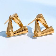 These elegant stainless steel earrings feature a geometric triangle design and are gold-plated for a luxurious finish. Weighing 6 grams each, they measure 14/15 cm in length, making them a striking accessory for any outfit. Weight: 6g. Material: 18K PVD Gold Plated Stainless Steel. Care Instructions:  * Protect your jewelry from scratches.  * Avoid exposure to harsh chemicals.  * Store your jewelry away from direct sunlight in a microfiber pouch.  * Clean with warm water and detergent-free soap; Elegant Triangle Metal Earrings, Gold Triangle Metal Earrings, Triangle Gold Metal Earrings, Gold Triangle Minimalist Earrings, Minimalist Gold Triangle Earrings, Modern Triangle Metal Earrings, Modern Triangle Earrings For Party, Modern Triangle Party Earrings, Modern Gold Geometric Earrings