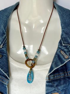 Simple but eye-catching lariat necklace with a brilliant 1 1/2" Blue Lace Agate pendant and a 1" ring of Mother of Pearl for closing, along with blue patina Bronze beads and a blue patina charm to add more color. All on 2mm distressed brown leather cord. To wear place open necklace around neck, then put pendant thru ring, and adjust to your liking. No lead or nickel used. Please use the Last On, First Off approach. Stones discolor with lotions, perfumes, hairspray, sweat, chlorine, even some soaps, and will break if dropped. Bohemian Teardrop Jewelry With Adjustable Chain, Bohemian Jewelry With Adjustable Teardrop Chain, Adjustable Teardrop Lariat Necklace, Bohemian Adjustable Lariat Drop Necklace, Adjustable Bohemian Lariat Drop Necklace, Bohemian Blue Jewelry With Sliding Knot, Blue Bohemian Jewelry With Sliding Knot, Bohemian Adjustable Beaded Necklace With Teardrop Pendant, Adjustable Bohemian Beaded Necklace With Teardrop Pendant