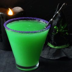 a green drink sitting on top of a table next to a black bag and candle