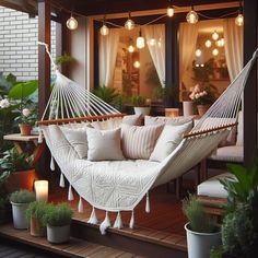 a white hammock sitting on top of a wooden deck next to potted plants