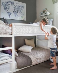 two children are playing on the bunk beds in this bedroom with grey walls and white furniture