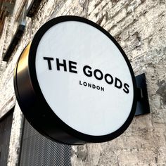 the goods sign is mounted to the side of a building with brick walls and windows