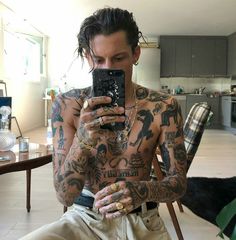 a tattooed man taking a selfie with his cell phone