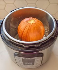 an orange pumpkin sitting in the middle of a crock pot on top of a counter