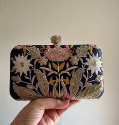 INTRODUCING VALLETA Exuding elegance, this clutch bag is crafted from luxurious dark blue silk and adorned with intricate gold dabka zardozi embroidery. Delicate pearls, shimmering cut dana, and sparkling sequins add opulence, while a charming rose button closure completes the look. Perfect for adding a touch of floral glamour to any ensemble, this accessory is a timeless statement piece. Dimensions: 20 x 12 x 5cm aprox Fits iPhone and similar sized phones Comes with  * Detachable chain * Gift b Bridal Clutch Bag, Zardozi Embroidery, Wedding Bags, Animal Bag, Scented Sachets, Gold Clutch, Bridal Clutch, How To Make Ribbon, Wedding Bag