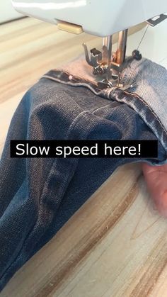 someone using a sewing machine to sew jeans on the floor with text overlay that reads slow speed here