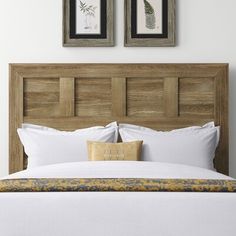 two framed pictures hang above a bed with white linens and yellow pillows on it