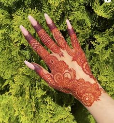 henna on the palm of a woman's hand with green foliage in the background