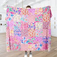 a person holding up a pink and blue quilt