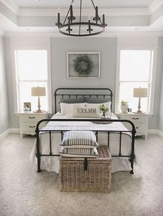 a bed room with a neatly made bed next to two windows and a ceiling fan