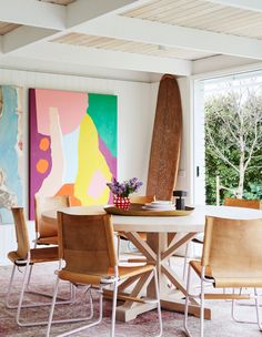 a dining room table with four chairs and a surfboard on the wall behind it