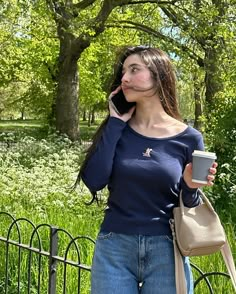 a woman is talking on her cell phone while holding a coffee cup in her hand