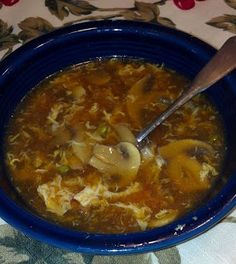 a blue bowl filled with soup on top of a table next to a wooden spoon