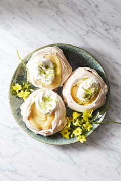 three desserts on a plate with yellow flowers and green garnish around them